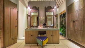 A bathroom with a wooden vanity, two mirrors, a sink, and a stool.