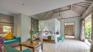 A spacious room with a bed, a sofa, a coffee table, and a large window.
