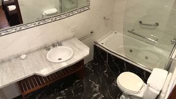 A bathroom with a marble vanity, a bathtub, and a toilet.
