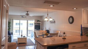 A kitchen with a central island, dining table, chairs, and a ceiling fan.