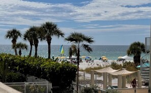 A beach view with palm trees, beach umbrellas, and a clear sky. - House Of The Sun #212GV (Sarasota)