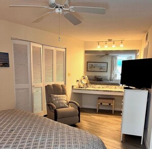 A bedroom with a bed, a chair, a desk, a television, and a ceiling fan. - House Of The Sun #212GV (Sarasota)