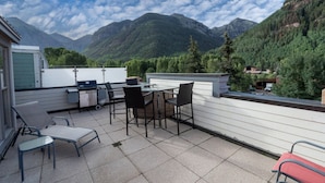A terrace with a table and chairs, a grill, and a view of mountains. - Willow 302 2 Bedroom/2 1/2 Bath Condo (Telluride)