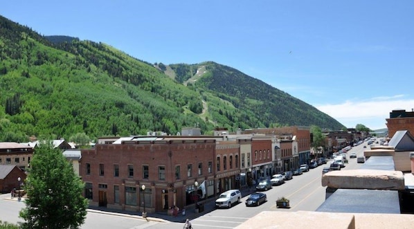 Une rue bordée d’immeubles en briques, un ciel dégagé et une montagne en arrière-plan.