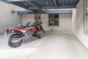 A covered parking area with two off-road motorcycles parked.