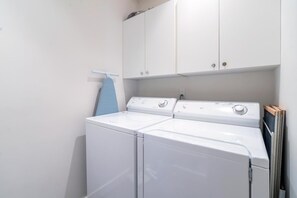 A laundry area with two stacked washers and dryers, a blue towel hanging on a rack, and white cabinets above. - Willow 302 2 Bedroom/2 1/2 Bath Condo (Telluride)