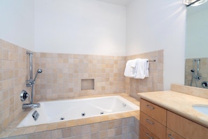 A bathroom with a bathtub, a shower, and a vanity with drawers.