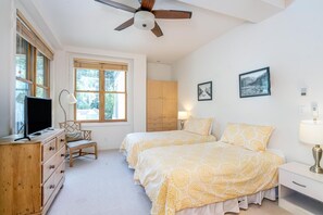 A bedroom with two beds, a ceiling fan, a TV, a wooden dresser, and a window with blinds. - Willow 302 2 Bedroom/2 1/2 Bath Condo (Telluride)