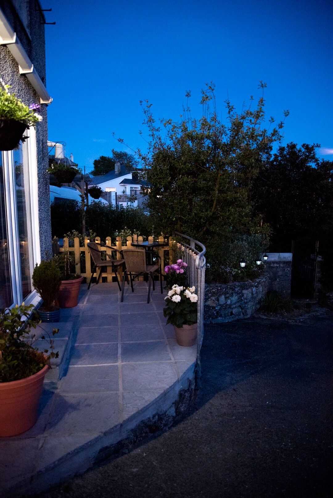 A patio area with outdoor seating, potted plants, and a wooden fence.