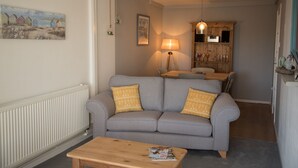 A living room with a grey sofa, a wooden coffee table, a lamp, and a painting on the wall.