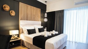 A modern hotel room with a large bed, a bedside table with a lamp, a wall-mounted air conditioner, and a view of the outdoors through sheer curtains. - Acropolis Panoramic View Exclusive Apartment | 3 Falirou str 11742 Athens (Athina)