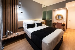 A modern hotel room with a large bed, bedside table, mirror, and a desk with a chair. - Acropolis Panoramic View Deluxe Apartment | 3 Falirou str 11742 Athens (Athina)