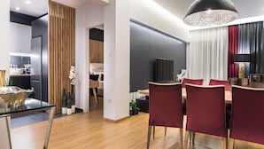 A modern kitchen with a refrigerator, wooden panel wall, and a dining area with a table and chairs. - Acropolis Panoramic View Exclusive Apartment | 3 Falirou str 11742 Athens (Athina)
