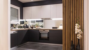 A modern kitchen with white cabinets, a wooden countertop, and a built-in oven. - Acropolis Panoramic View Exclusive Apartment | 3 Falirou str 11742 Athens (Athina)