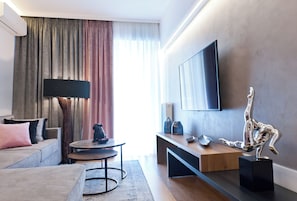 Een moderne woonkamer met een bank, salontafel, televisie en decoratieve accessoires.