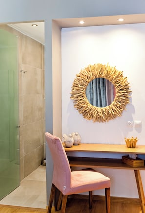 A bathroom with a shower, a vanity with a mirror, a pink chair, and a wooden desk. - Acropolis Panoramic View Deluxe Apartment | 3 Falirou str 11742 Athens (Athina)