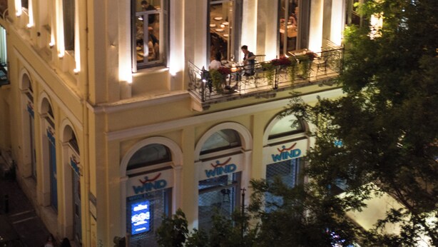 A building with a balcony and multiple windows, some with signs reading 'WIND'. - Acropolis Panoramic View Exclusive Apartment | 3 Falirou str 11742 Athens (Athina)