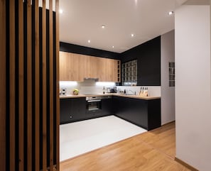 A modern kitchen with wooden cabinets, a white countertop, and a black backsplash.