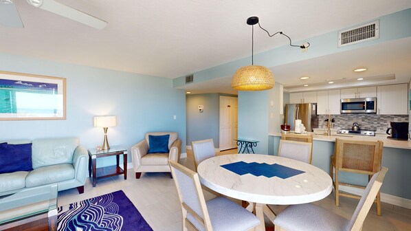 A modern living room with a round table, a sofa, and a dining area with chairs.