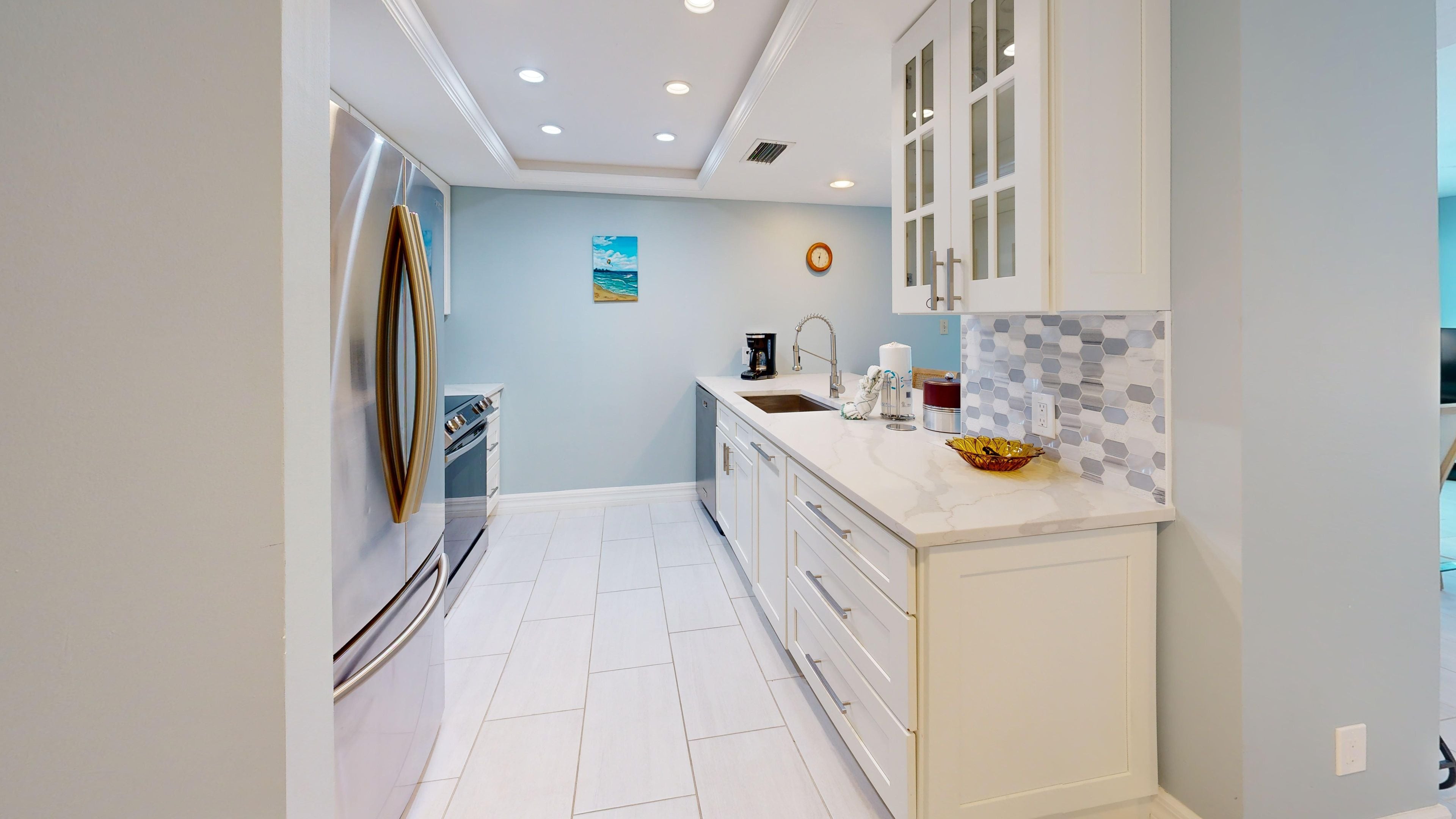A modern kitchen with white cabinetry, a stainless steel refrigerator, and a tiled backsplash.