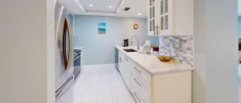 A modern kitchen with white cabinetry, a stainless steel refrigerator, and a tiled backsplash.