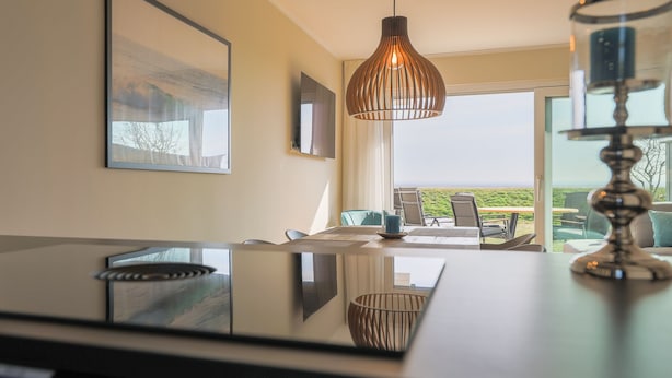 Cozinha moderna com uma ilha grande, iluminação pendente e vista para o exterior.