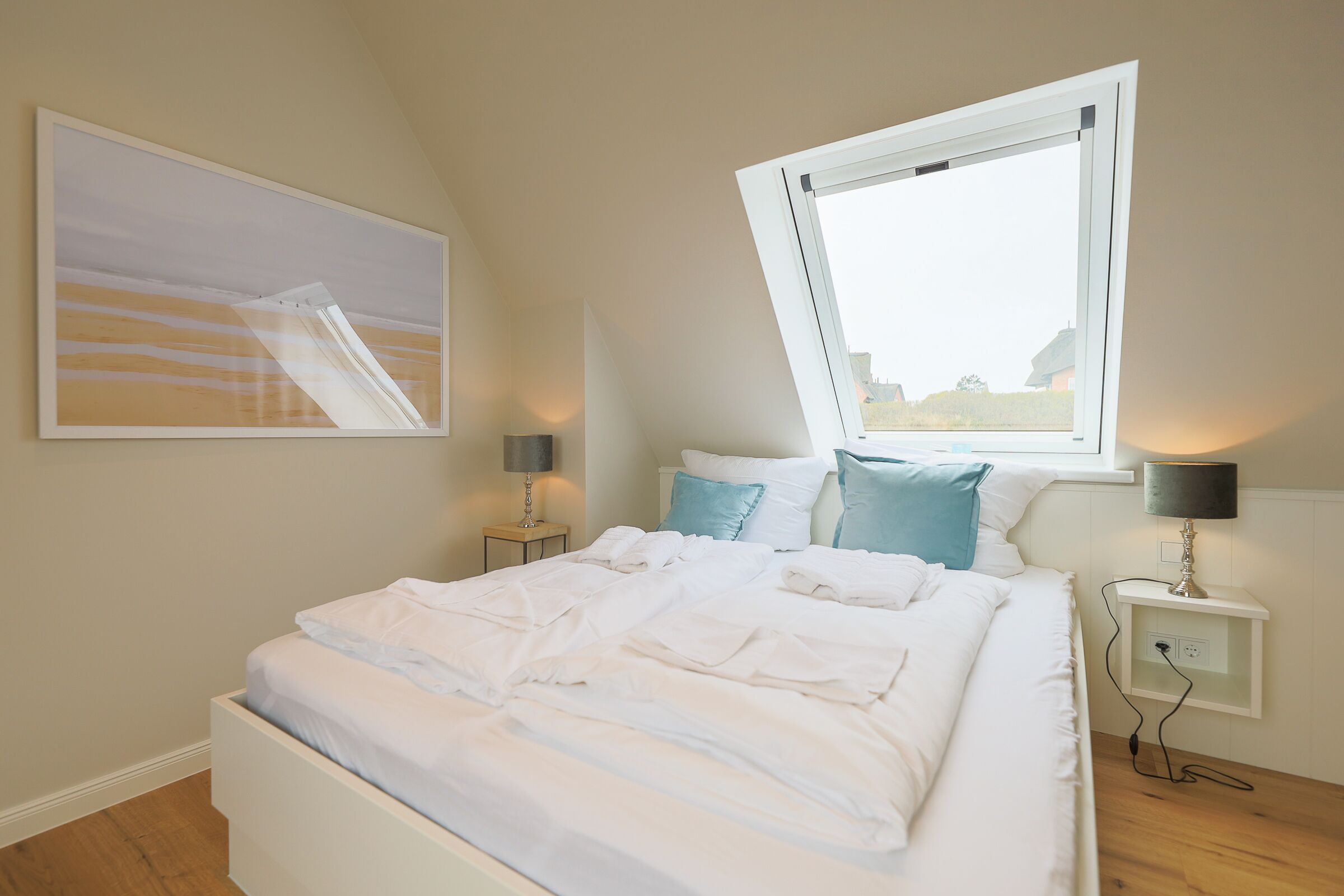 A bedroom with a bed, a window, a nightstand, and a wall-mounted lamp.