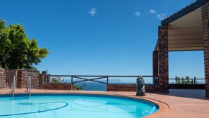 En swimmingpool med fri utsikt över havet och bergen i bakgrunden.