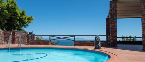 Une piscine offrant une vue dégagée sur l’océan et les montagnes en arrière-plan.