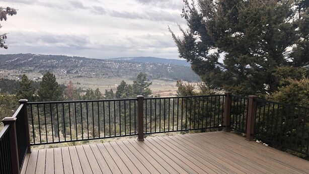 A wooden deck with a black railing overlooking a mountainous landscape. - Welcome to our Mountain Lake Getaway (White Sulphur Springs)