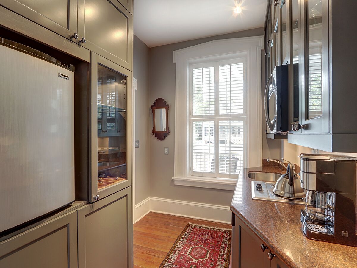 Una cocina con refrigerador, estufa y ventana con persianas.