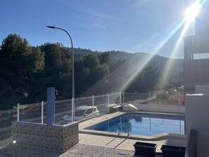 Relax by the serene pool surrounded by a forested hillside.