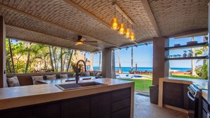 A modern kitchen with a large island, built-in appliances, and a view of the ocean. - Casa Palmar 3BR  · Remarkable 3BR, 2BA Beachfront Condo (Sayulita)