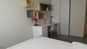 A bedroom with a bed, a desk with a chair, and a wardrobe. - Cocooning apartment 10 minutes from beaches (cabestany)