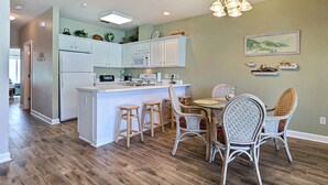 Una cucina moderna con mobili bianchi, un'isola centrale e sgabelli da bar.