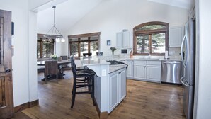 Una cocina amplia con una isla grande, suelo de madera y vistas al exterior gracias a amplios ventanales.