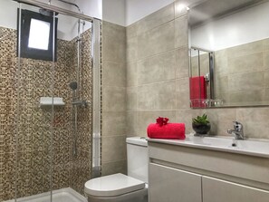 Ein Badezimmer mit Dusche, Toilette, Waschbecken und Spiegel.