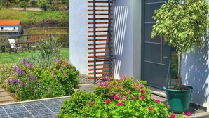 A modern building with a grey exterior, a wooden slatted structure, and a potted tree. - Modern Madeira house in Calheta, Madeira (Estreito da Calheta)