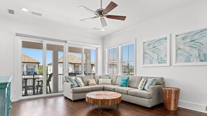 A spacious living room with a large sectional sofa, a round coffee table, and a ceiling fan. - ☀️ Sol Experience | Golf Cart & Heated Community Pool | FREE Golf (Miramar)