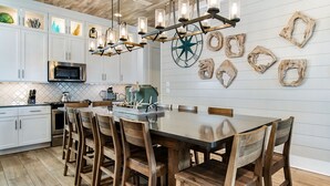A modern kitchen with white cabinetry, a central island, wooden chairs, and a chandelier. - ☀️ Sol Experience | Golf Cart & Heated Community Pool | FREE Golf (Miramar)
