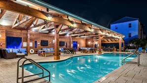 A swimming pool with a wooden deck and lounge area, surrounded by brick walls and wooden beams. - ☀️ Sol Experience | Golf Cart & Heated Community Pool | FREE Golf (Miramar)
