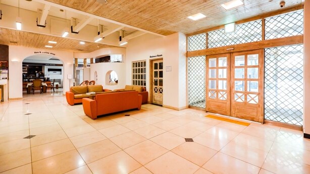 A hotel lobby with a wooden ceiling, a reception desk, a business room, and a seating area with a sofa. - Newvera Hotel (Cheongju)