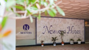 A Newvera Hotel reception area with a tiled wall, potted plants, and a logo. - Newvera Hotel (Cheongju)