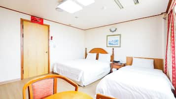A hotel room with two beds, a wooden door, a small table, and a chair.