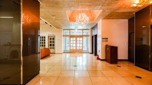A spacious lobby with a wooden ceiling, a chandelier, a reception desk, and a business room visible in the background. - Newvera Hotel (Cheongju)