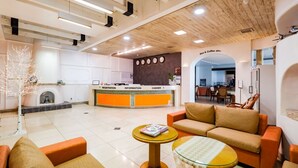 A modern hotel lobby with a reception desk, seating area, and a fireplace. - Newvera Hotel (Cheongju)