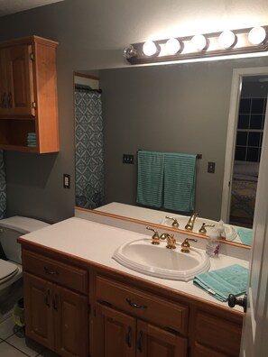A bathroom with a white sink, two gold faucets, a mirror, and a wooden vanity.