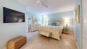 A bedroom with a bed, dresser, vanity, and a television. - House Of The Sun #410GV (Sarasota)