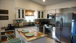 A modern kitchen with white cabinets, stainless steel appliances, and a central island with a cutting board. - Fall Specials Available! Pet Friendly! Steps to white sandy beaches and the bay!  Discounts applied for stays longer than 7 days and 30 days! (Bradenton Beach)