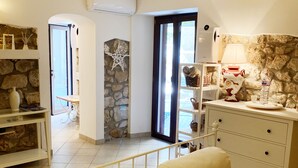 A bedroom with a bed, bedside tables, a dresser, and a stone wall. - Circeii, apartment with bedroom, living room and exterior with bathtub (San Felice Circeo)